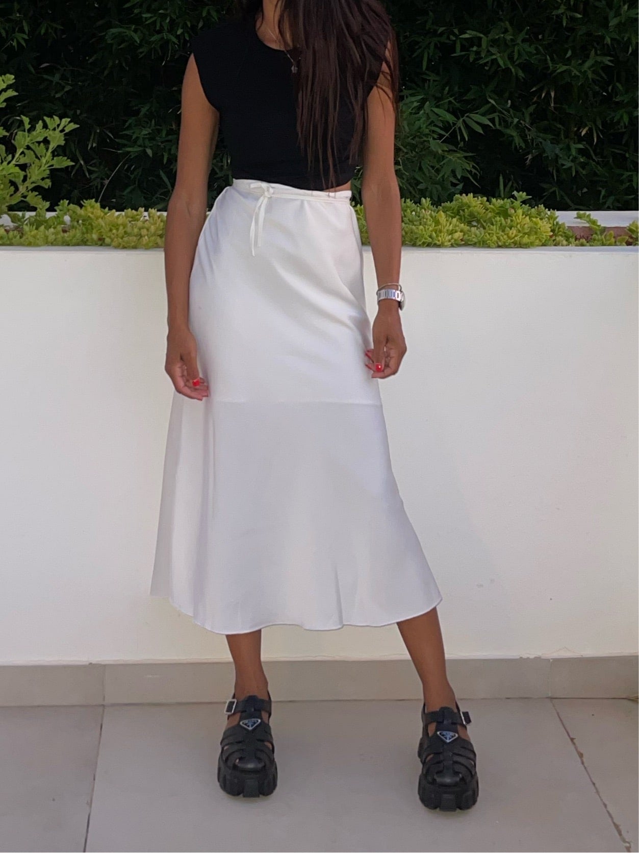 Jupe blanche en satin mi-longue avec taille élastique et coupe évasée dans un décor extérieur