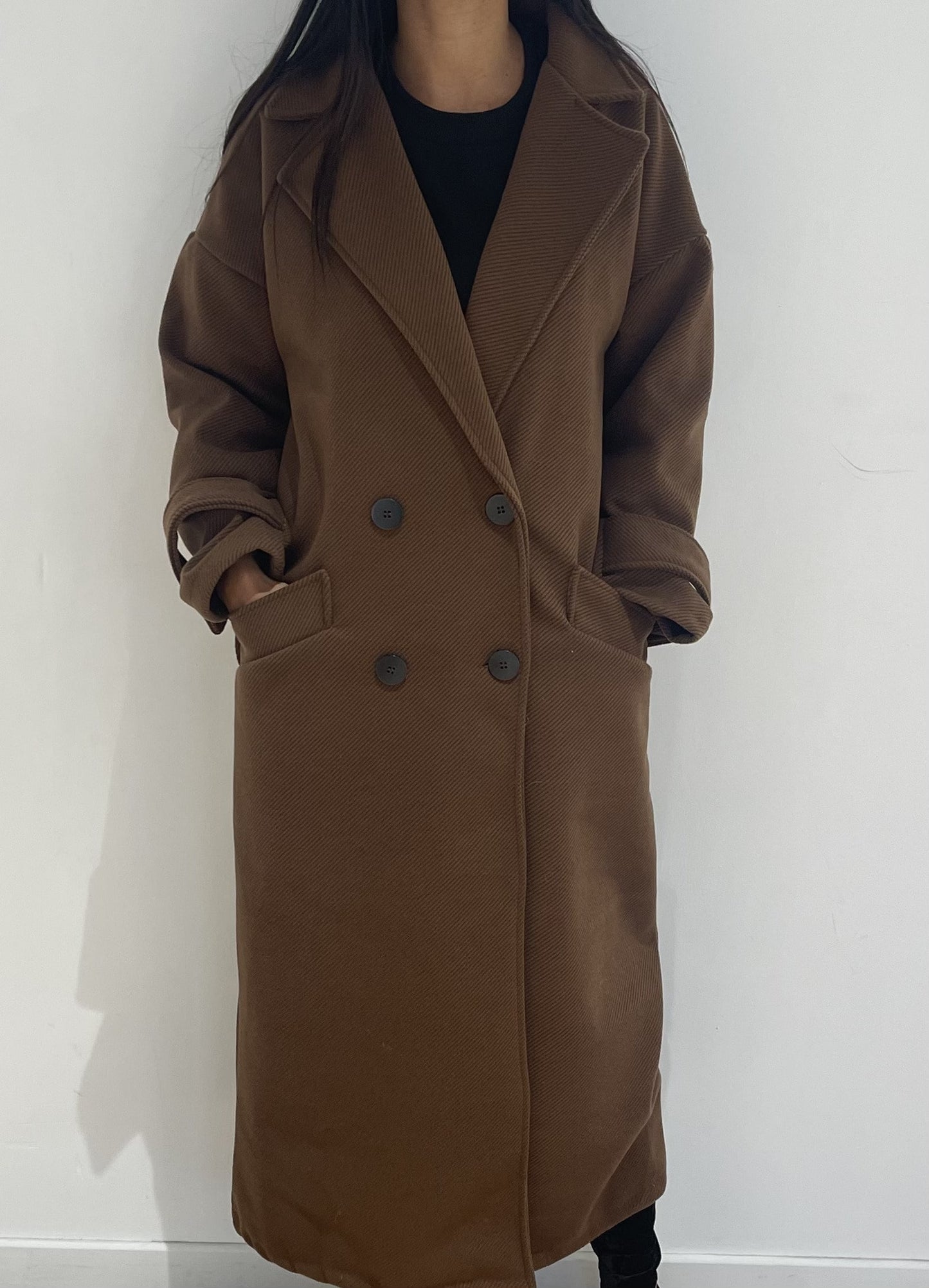 Manteau d'hiver marron pour femme, coupe longue et boutonnée.