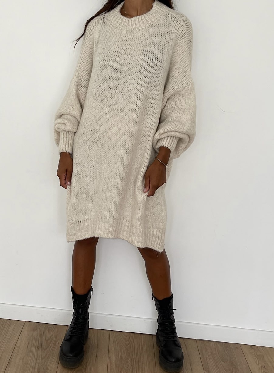 Une femme portant une robe-pull en tricot crème ample et confortable.