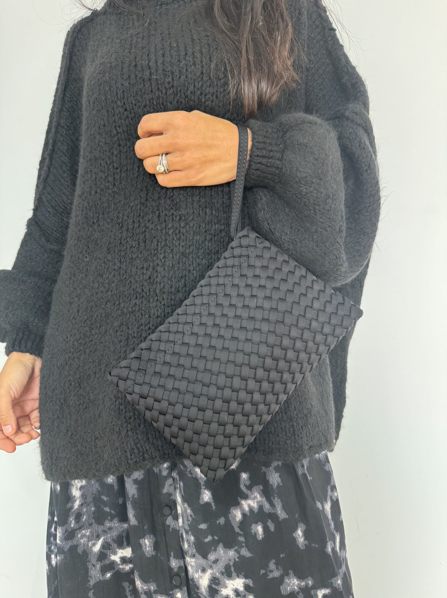 Sacs Tega pochette noir accroché à l'épaule, assorti à un pull sombre pour une allure urbaine moderne