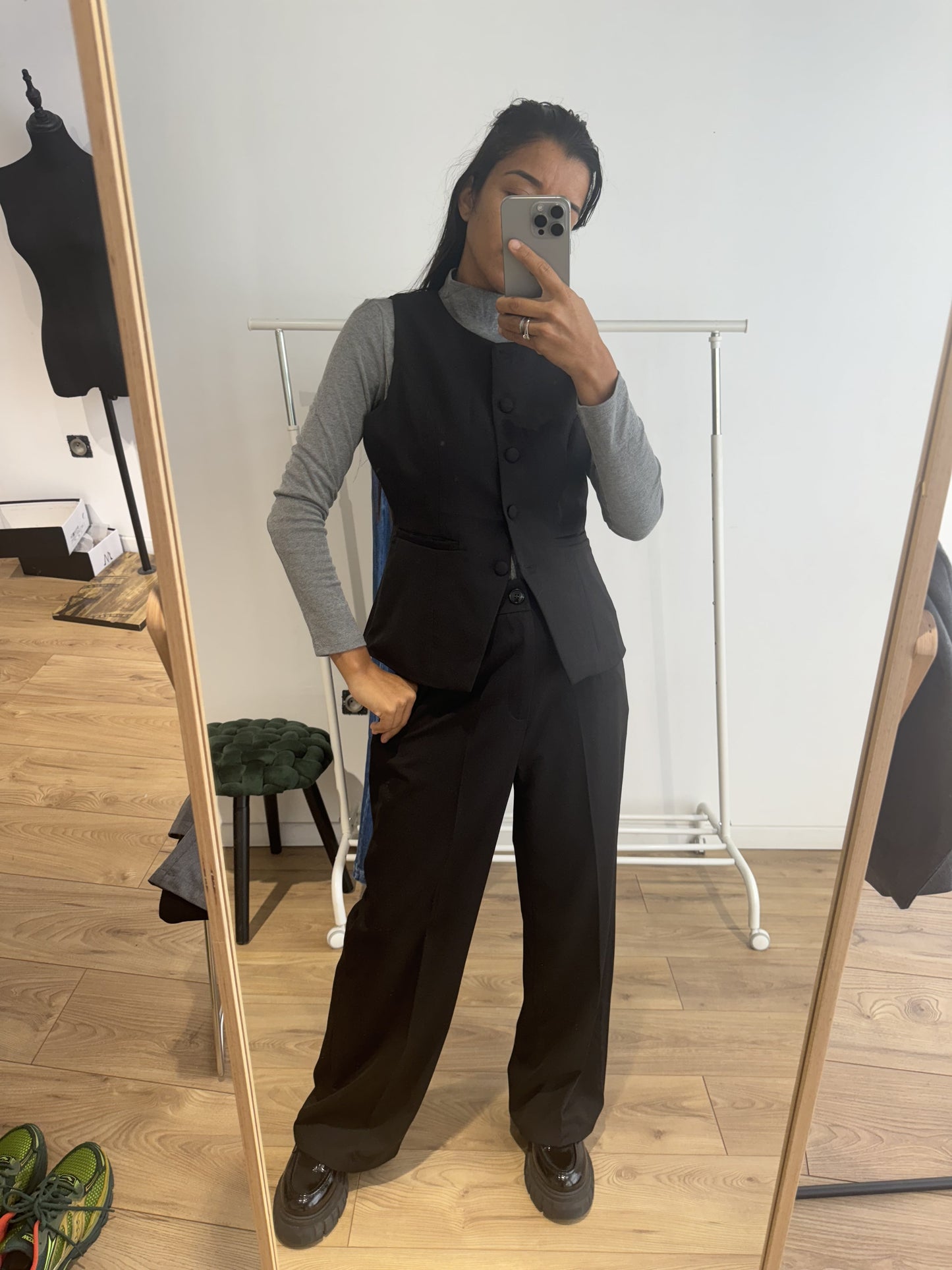 Femme portant un blazer sans manches noir avec un col roulé gris, vue de face.