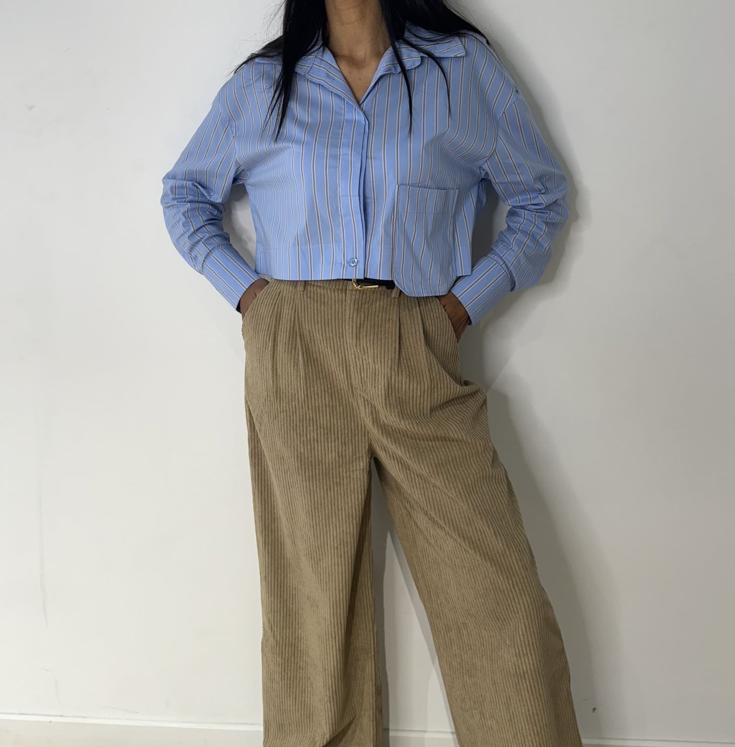 Femme portant une chemise à rayures bleues avec un pantalon beige
