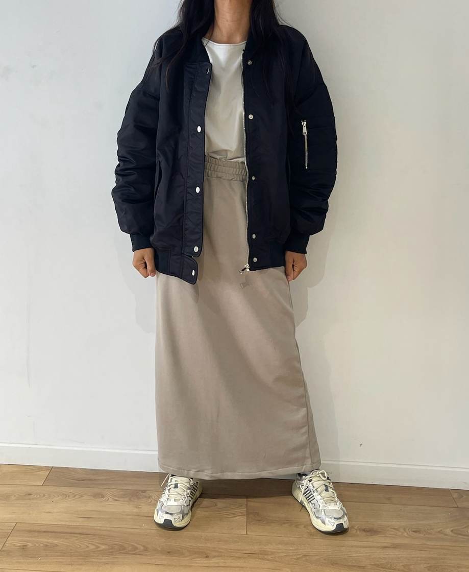 Femme en ensemble jupe et pull taupe avec veste noire