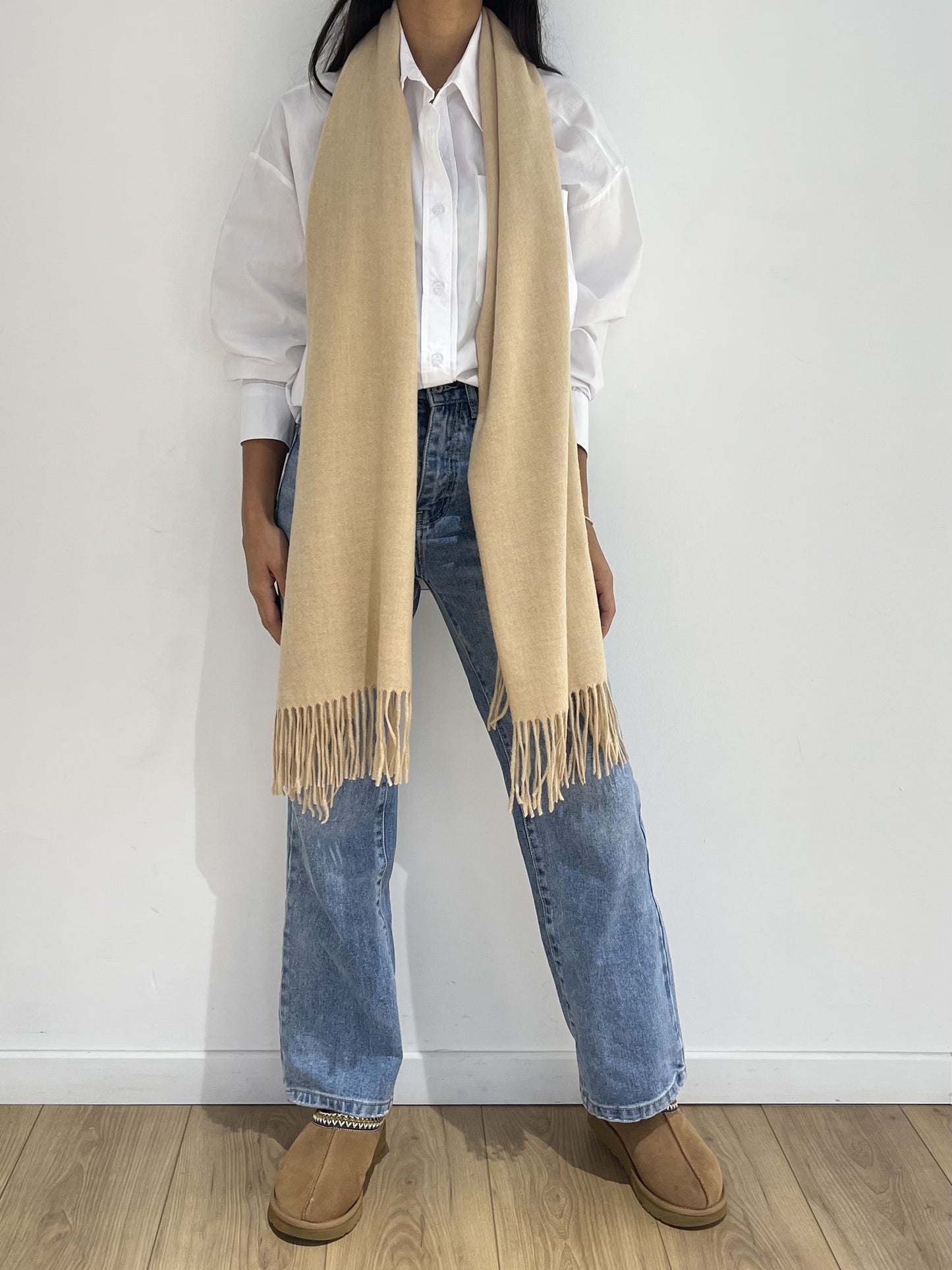 Étole femme marron à franges façon poncho drapée sur les épaules, combinée avec une tenue casual blanche et denim.
