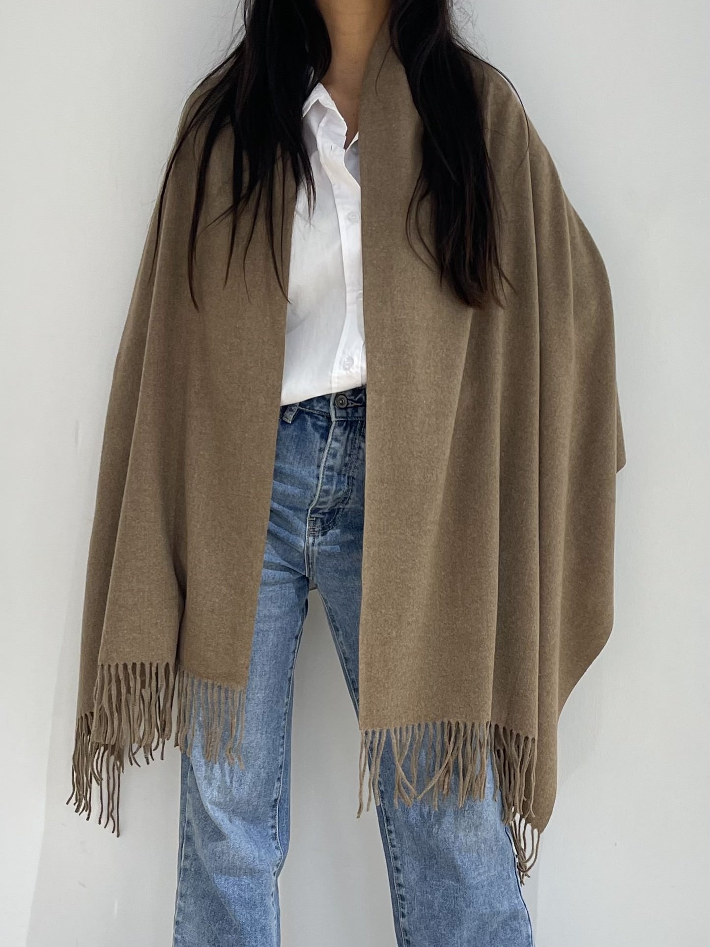 Étole femme marron à franges façon poncho drapée sur les épaules, combinée avec une tenue casual blanche et denim.