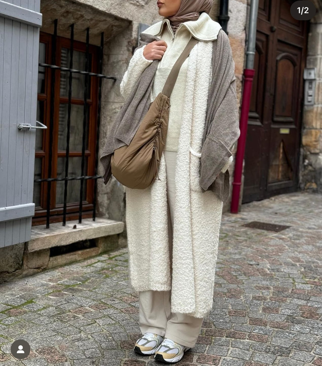 Femme portant un manteau long crème avec accessoires urbains