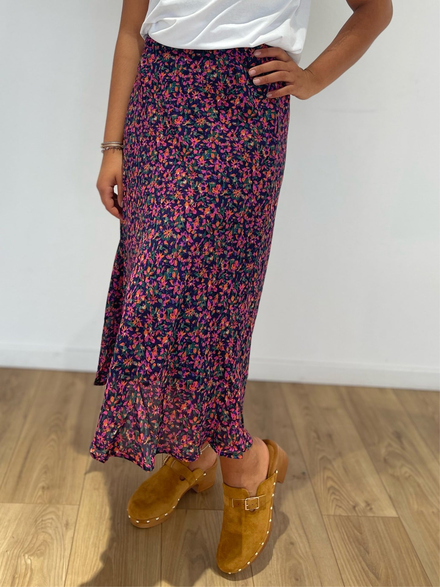 Jupe longue aux motifs floraux colorés pour femme, associée à des sabots marron clair