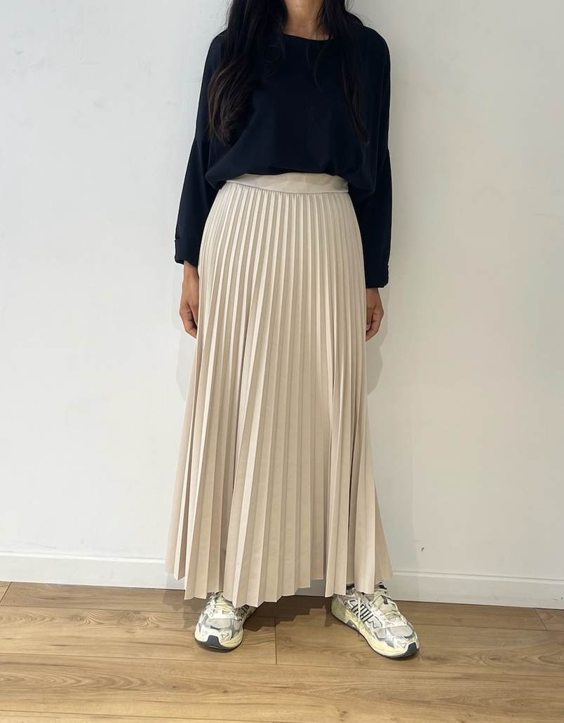 Vue arrière d'une jupe plissée beige avec un tee-shirt violet