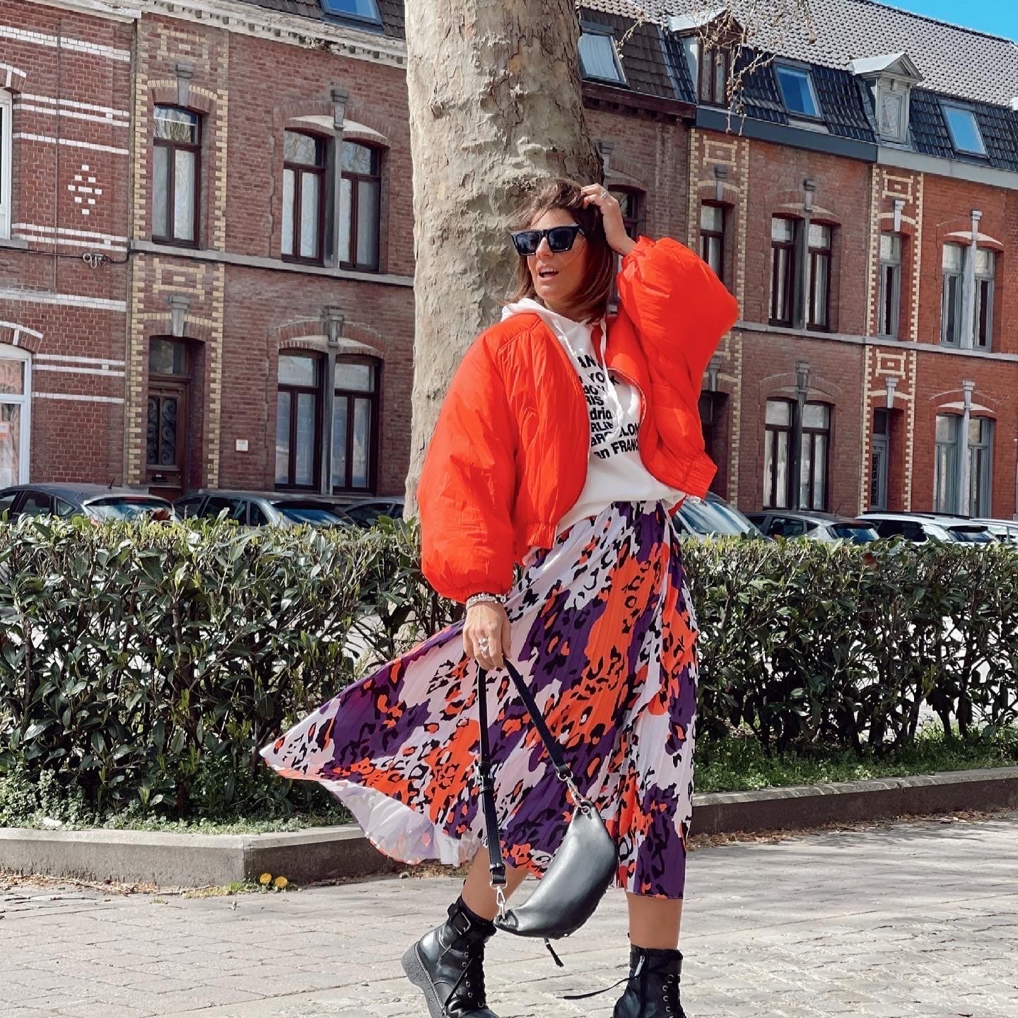 Femme portant une jupe plissée longue avec des motifs en orange, violet et blanc