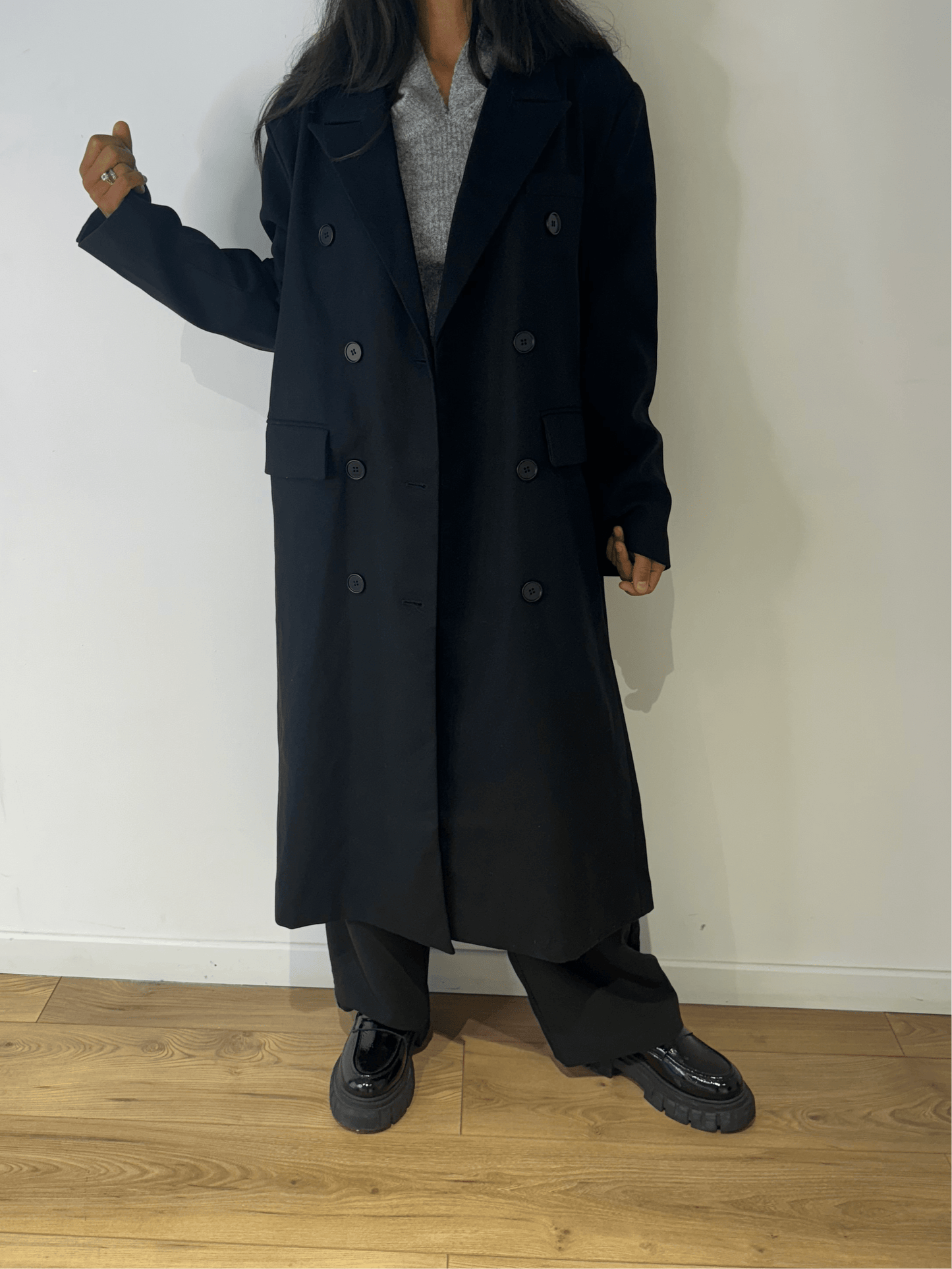 ue de profil d'une femme en manteau oversize noir, style moderne.