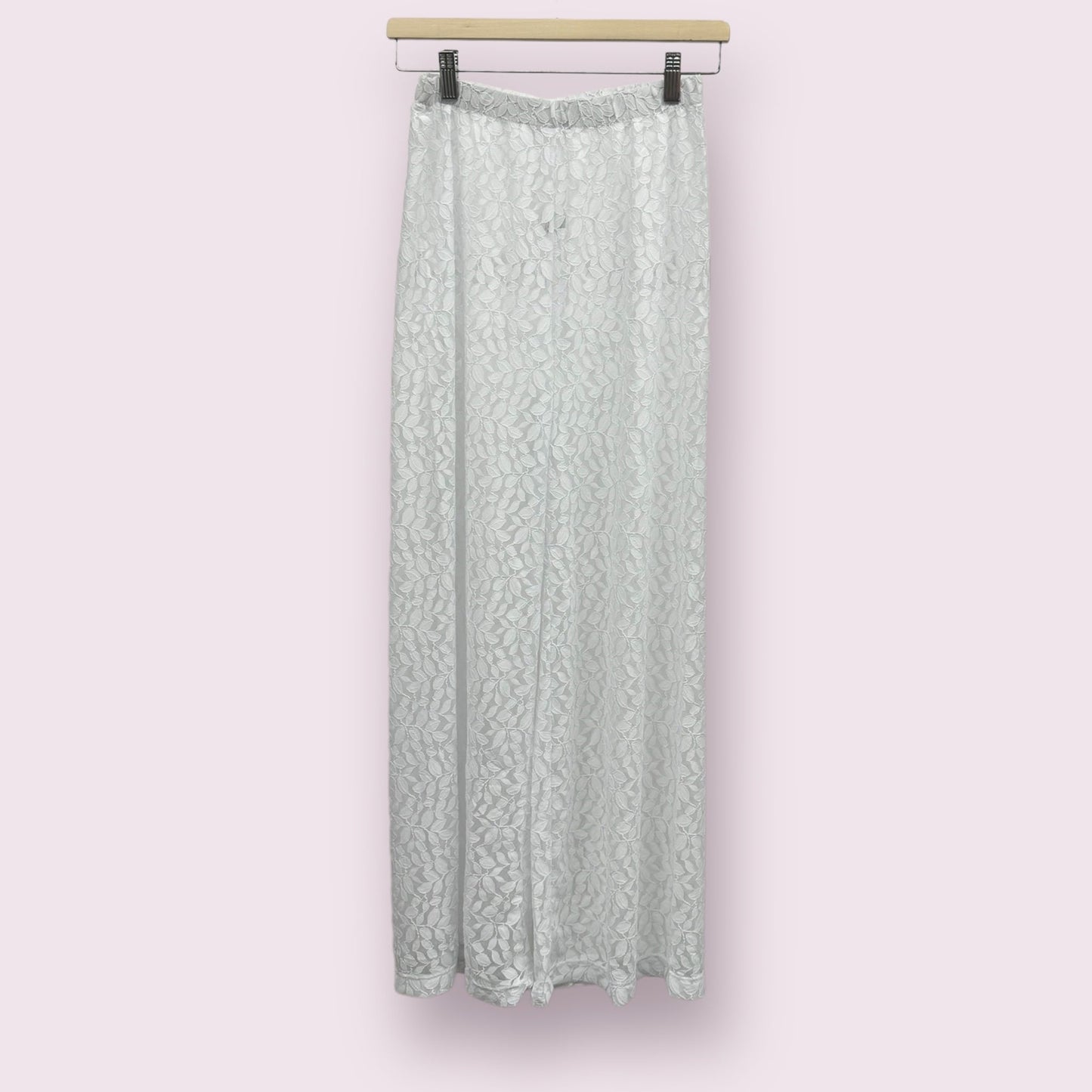 Pantalon de plage pour femme en blanc, sur un cintre.