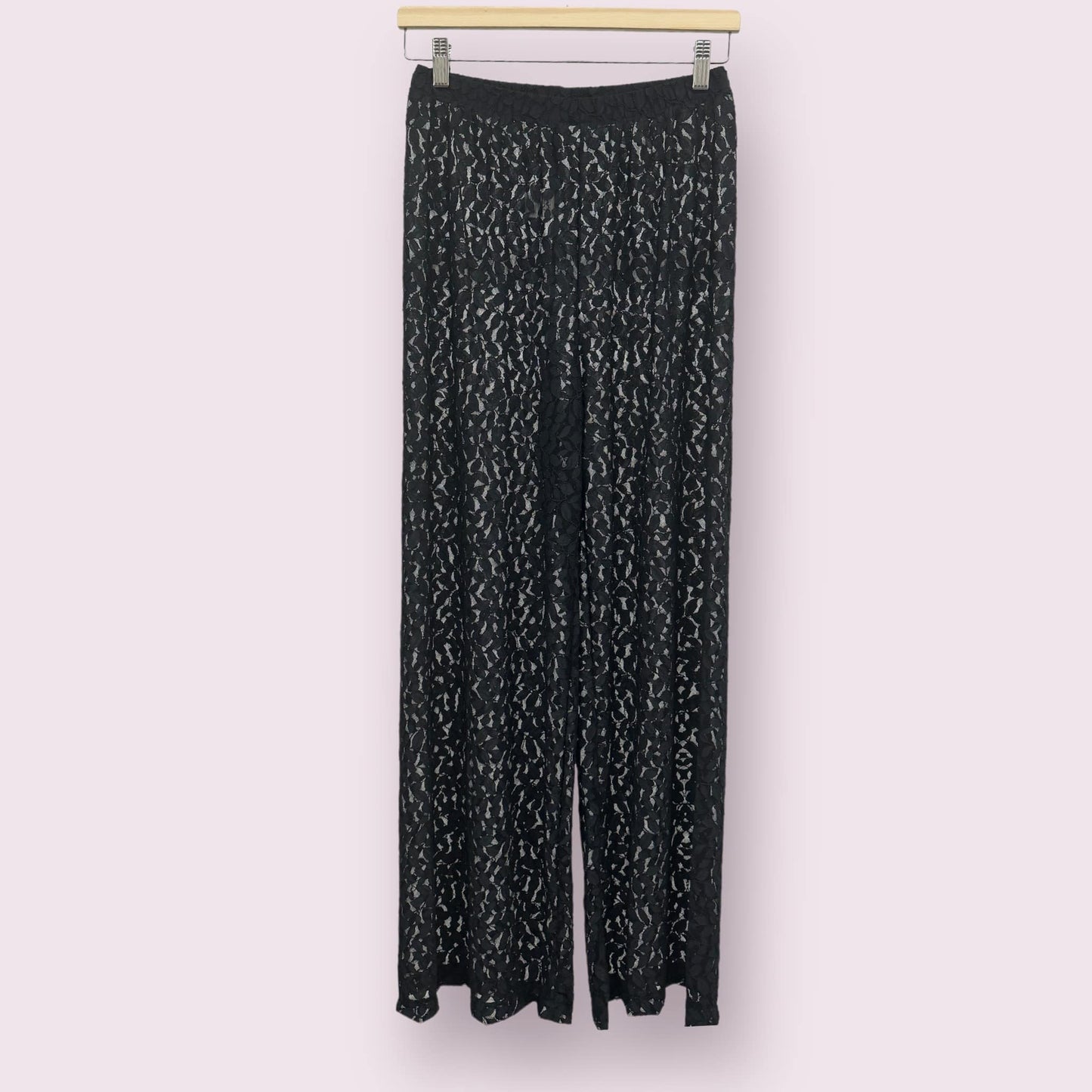 Pantalon de plage pour femme en noir, sur un cintre.