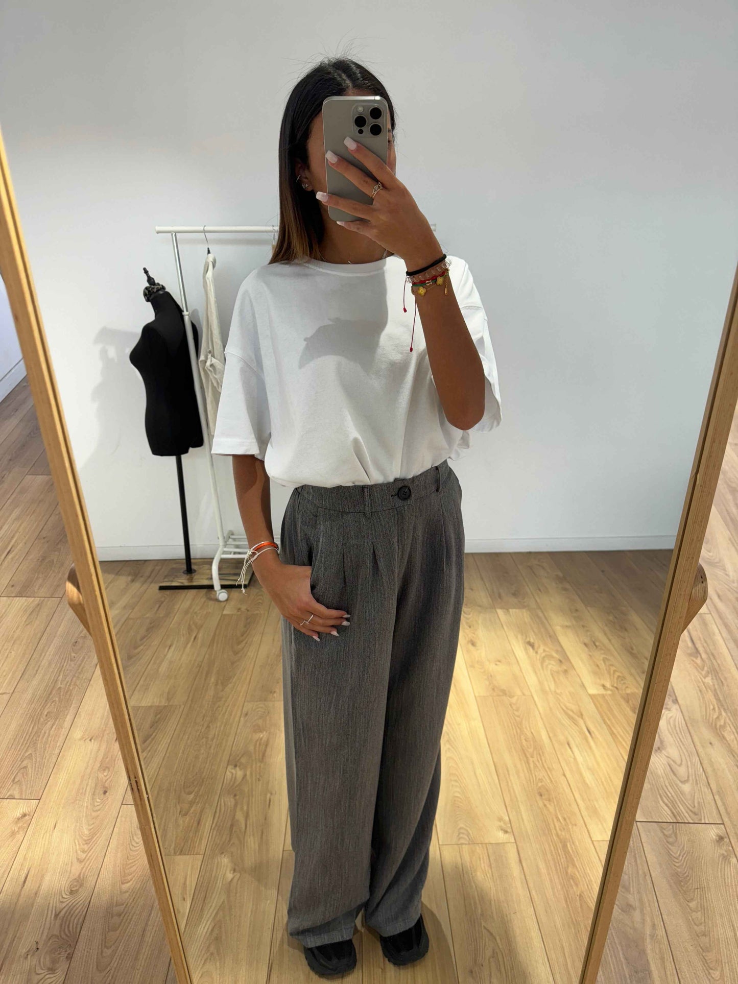 Femme portant un pantalon gris ample avec un t-shirt blanc, prise de vue de face.