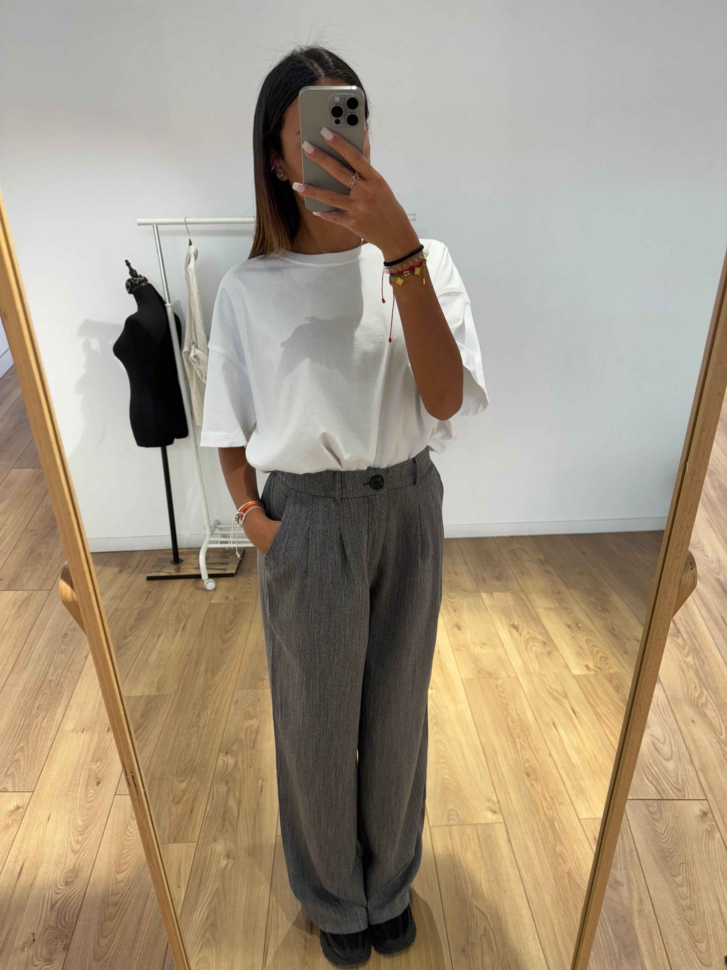 Femme portant un pantalon gris ample et un t-shirt blanc pour un look décontracté, vue de face.
