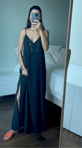 Miroir reflétant une robe noire à bretelles fines et sandales colorées.