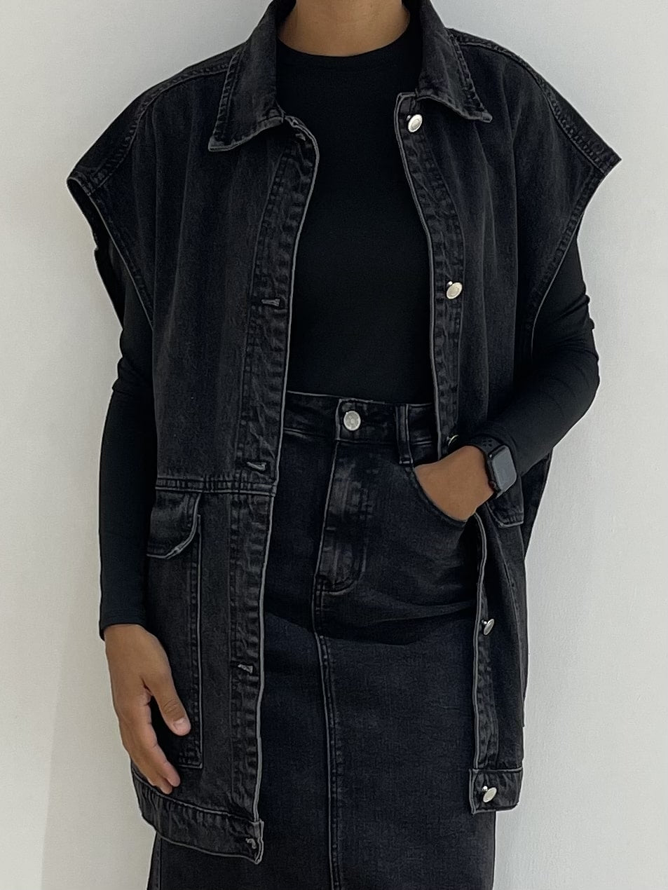 Femme portant une veste en jean noir sans manches ajustée