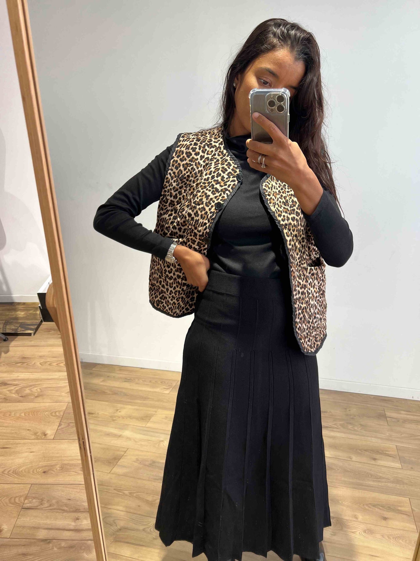 Femme portant une veste sans manches imprimée léopard avec une tenue noire, vue de face.