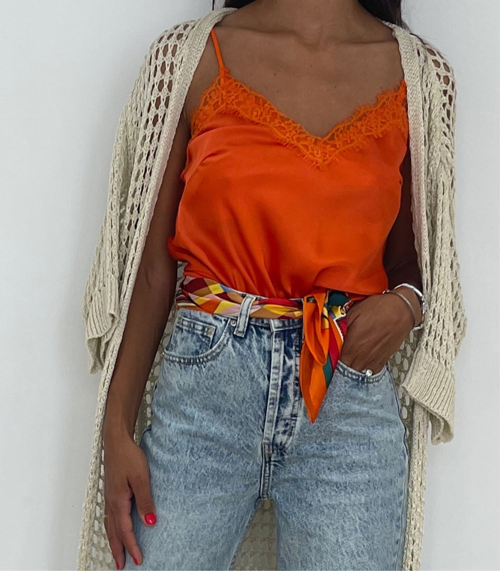 Caraco orange vif avec détails en dentelle, associé à un jean et une ceinture colorée