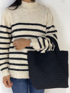 Pull marinière beige et noir avec sac tressé noir, combinant confort et style pour l'hiver 2024.