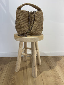 Sacs Tega mini en teinte camel posé sur un tabouret en bois, mettant en valeur son design tressé et sa portabilité.