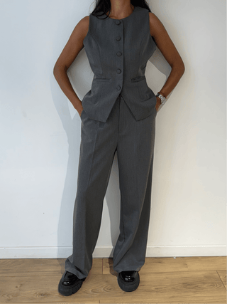 Femme portant un blazer sans manches gris, vue de face en gros plan.
