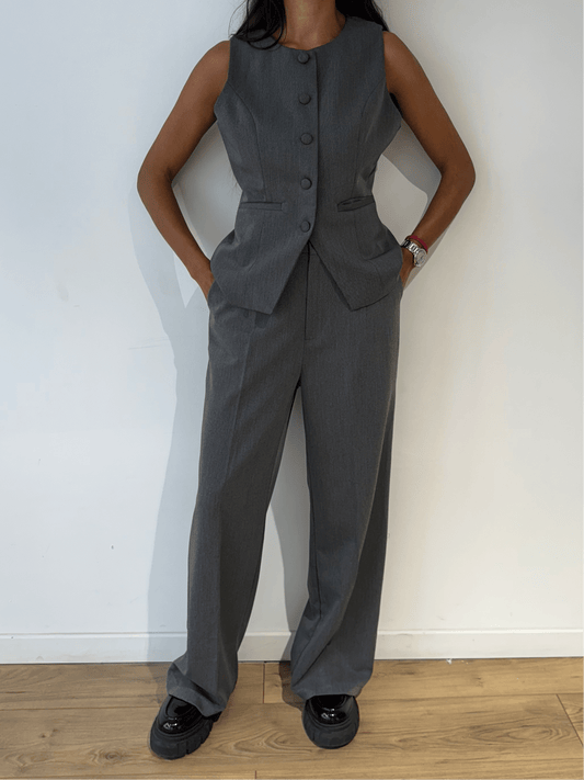 Femme portant un blazer sans manches gris, vue de face en gros plan.