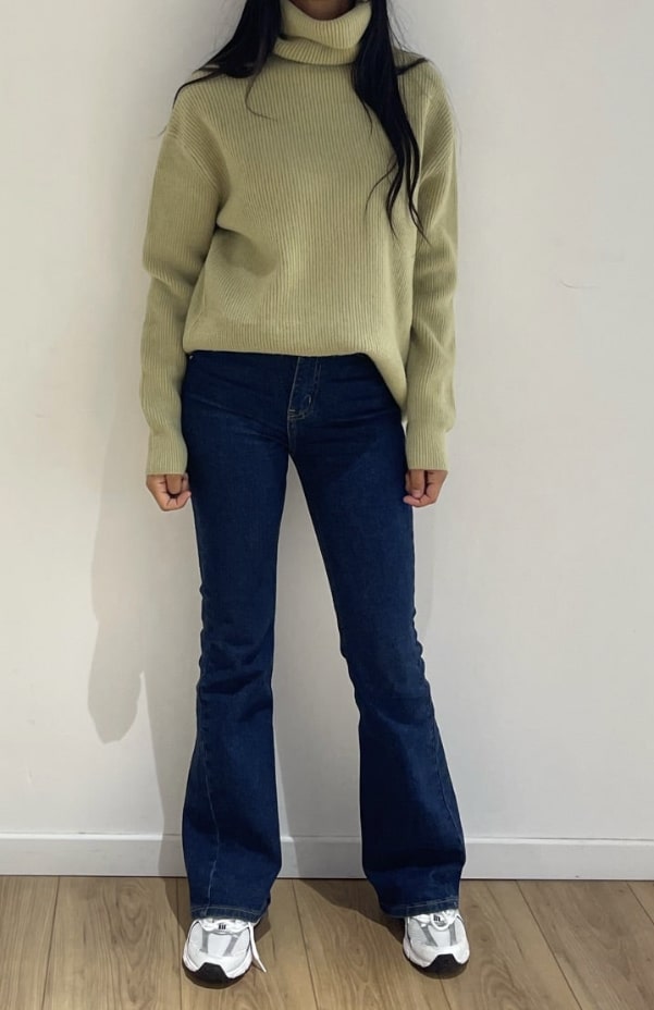 Col roulé pistache en maille côtelée porté avec des jeans denim et des baskets blanches