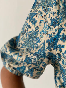 Gros plan du motif floral sur robe bleue.