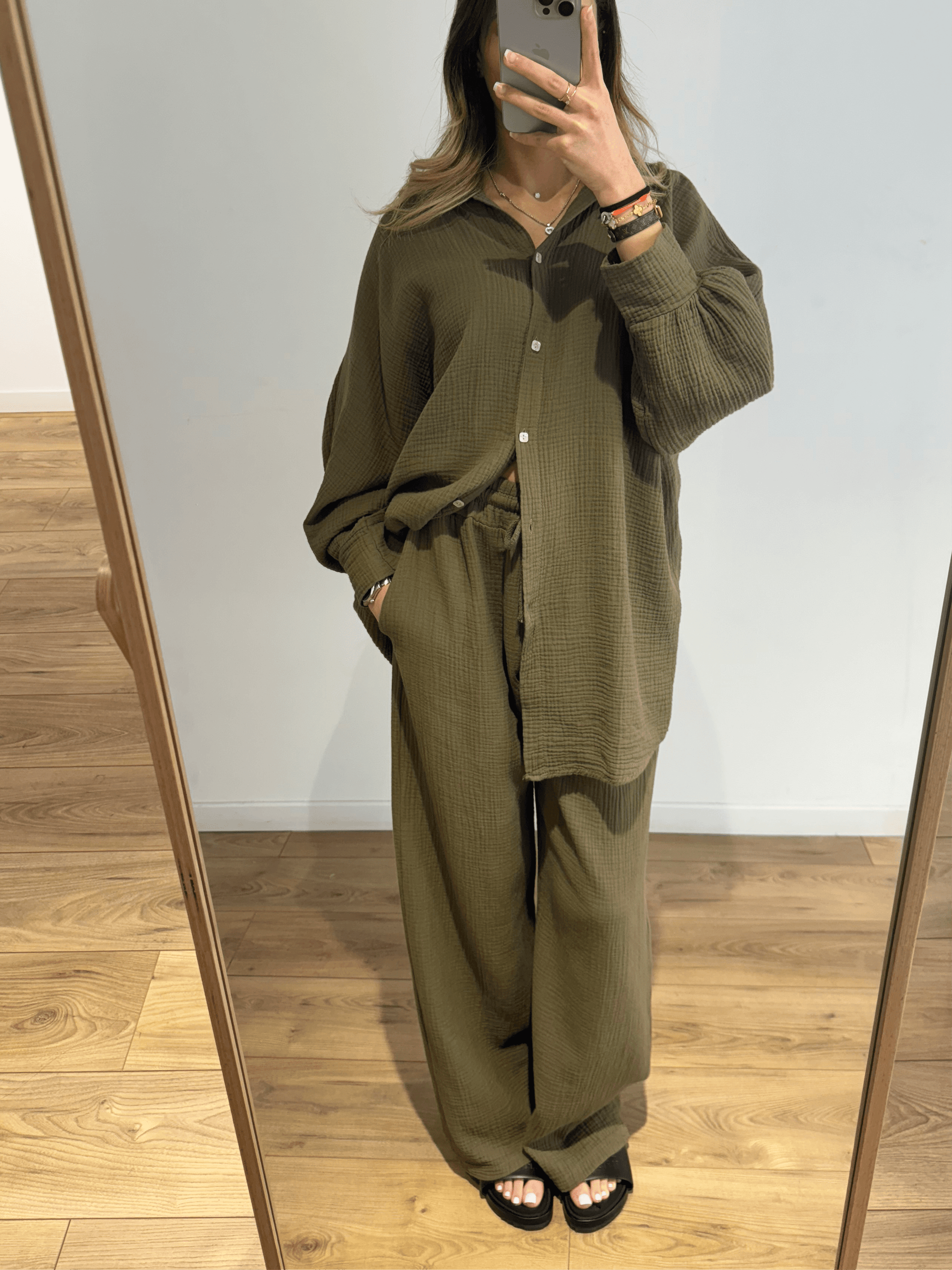 Femme portant un ensemble chemise et pantalon en gaze de coton vert kaki, prise en selfie devant un miroir.