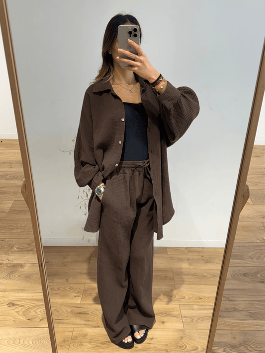 Femme portant un ensemble chemise et pantalon en gaze de coton marron, prise en selfie dans une pièce bien éclairée.