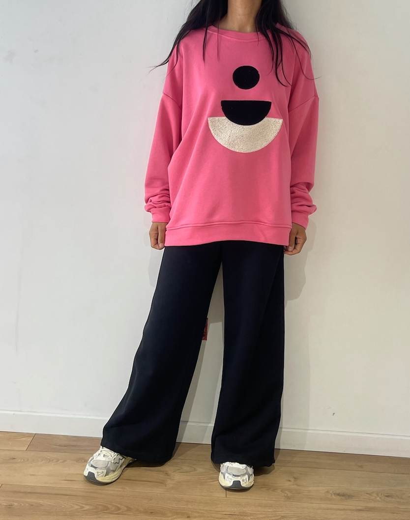 Femme portant un ensemble en coton rose et noir avec motif souriant, vue de face