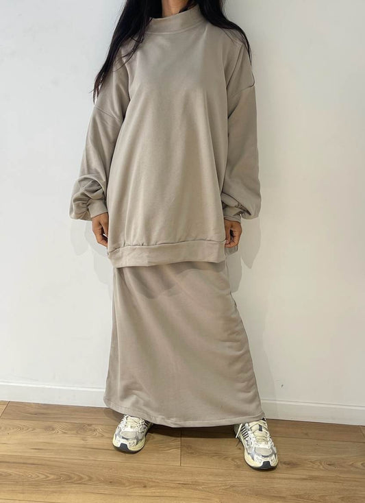 Femme debout en tenue décontractée beige, ensemble jupe et pull