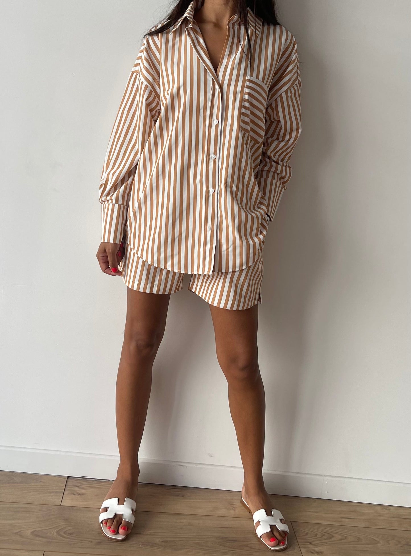 Femme dynamique en ensemble short à rayures beige et blanc avec chemise oversize.