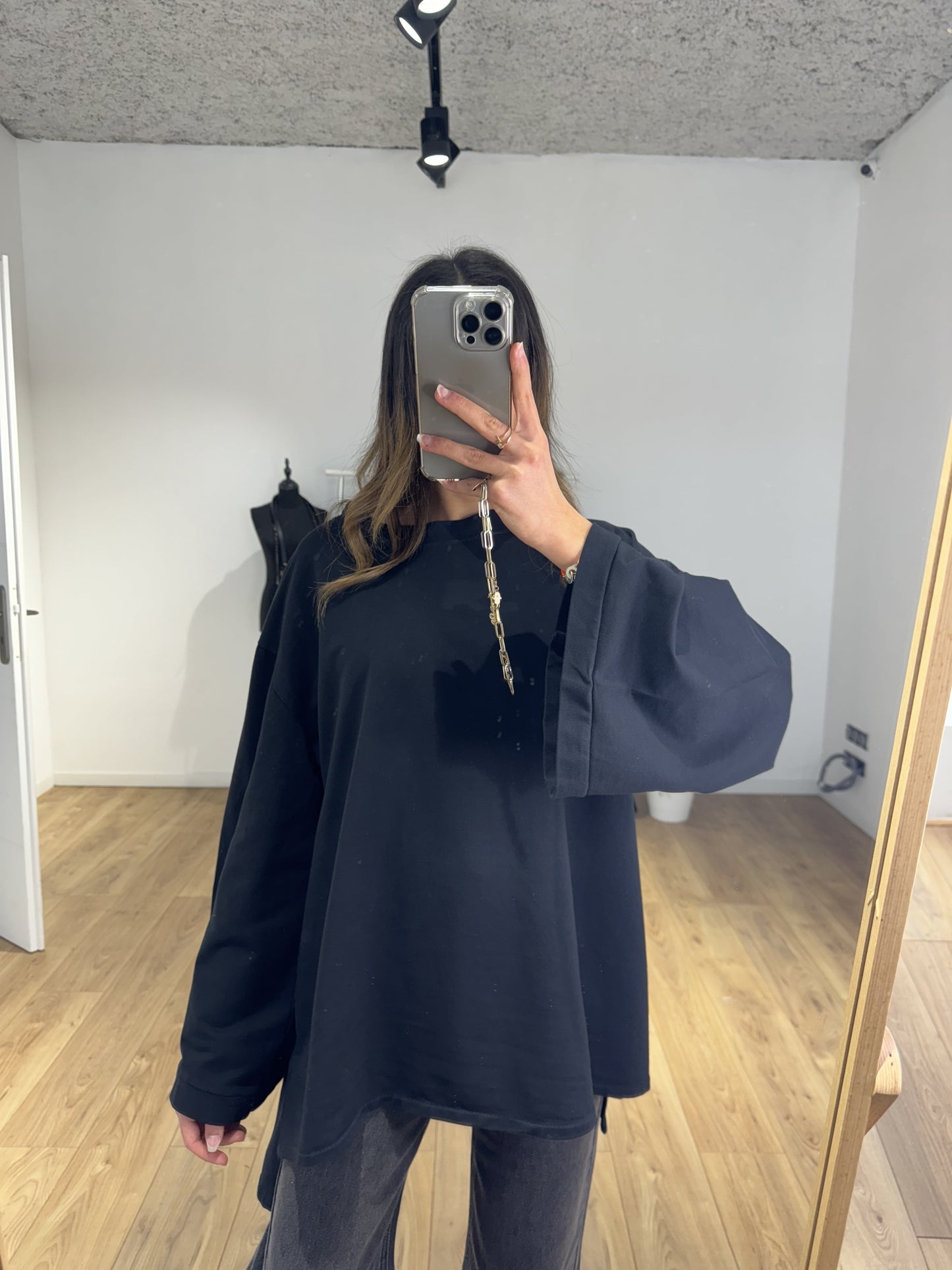 Réflection de femme en haut oversize noir avec téléphone