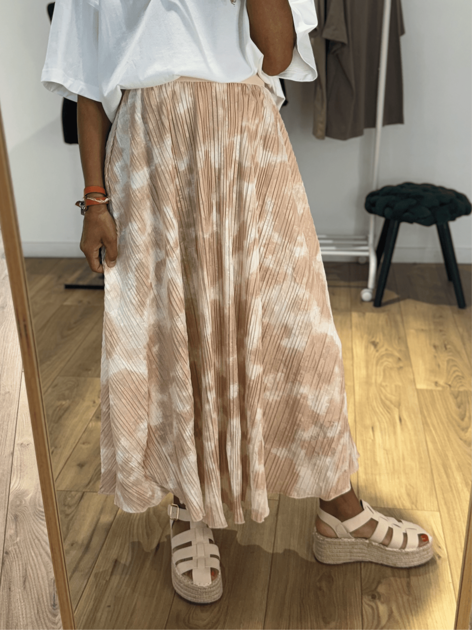 Femme en jupe longue plissée beige avec motif tie & dye, vue de face.