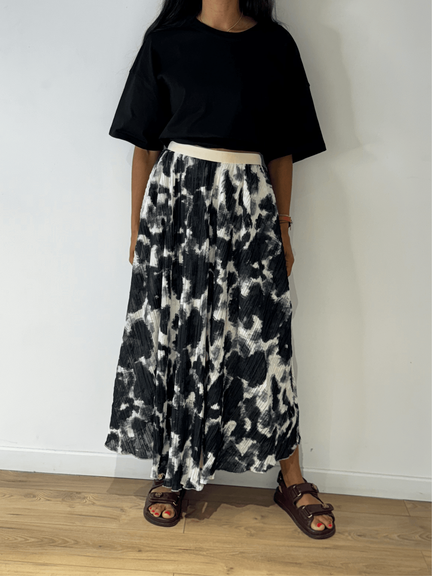 Femme portant une jupe longue plissée noir et blanc en tie & dye, vue de face.
