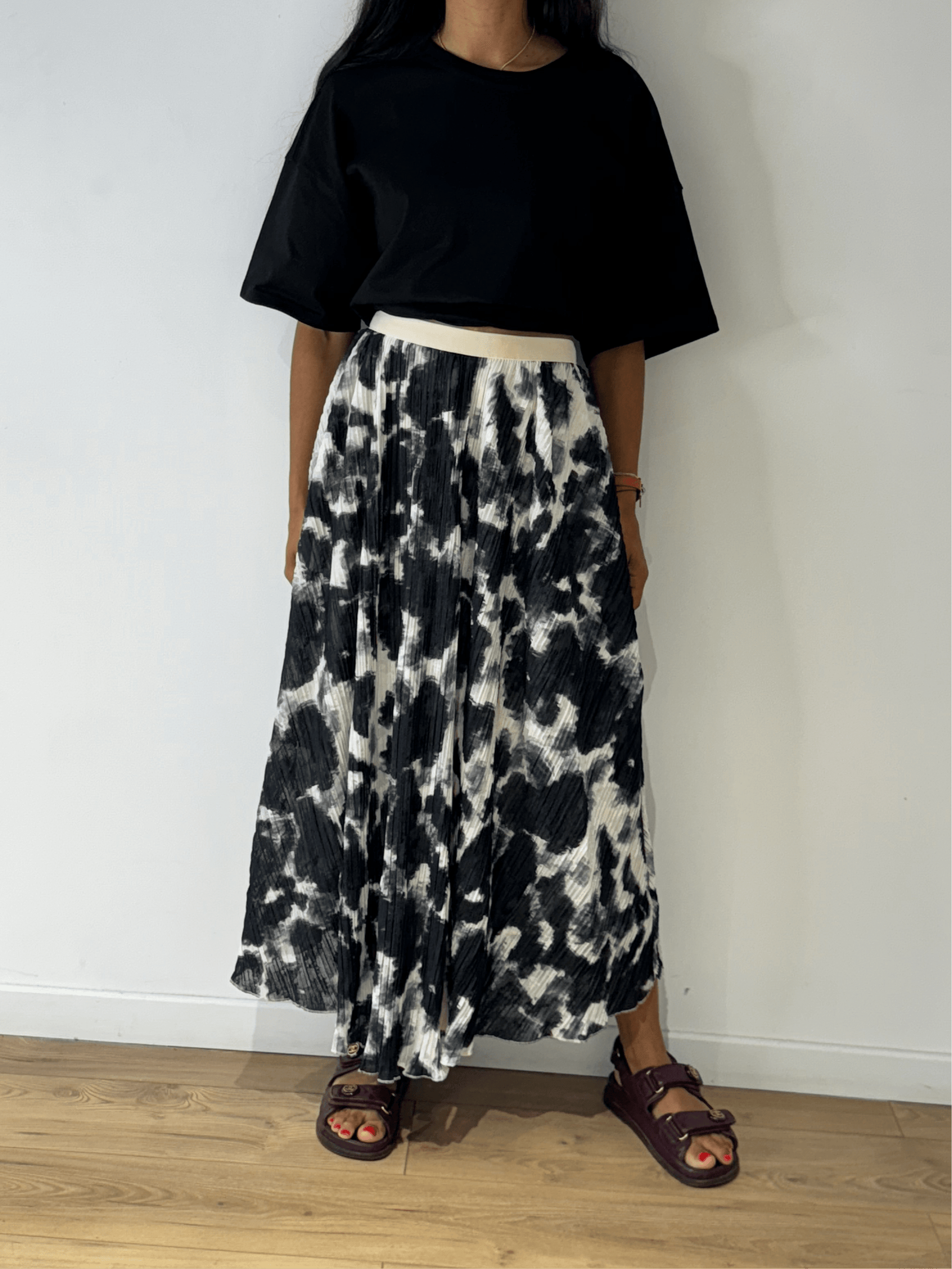 Femme portant une jupe longue plissée noir et blanc en tie & dye, vue de face.