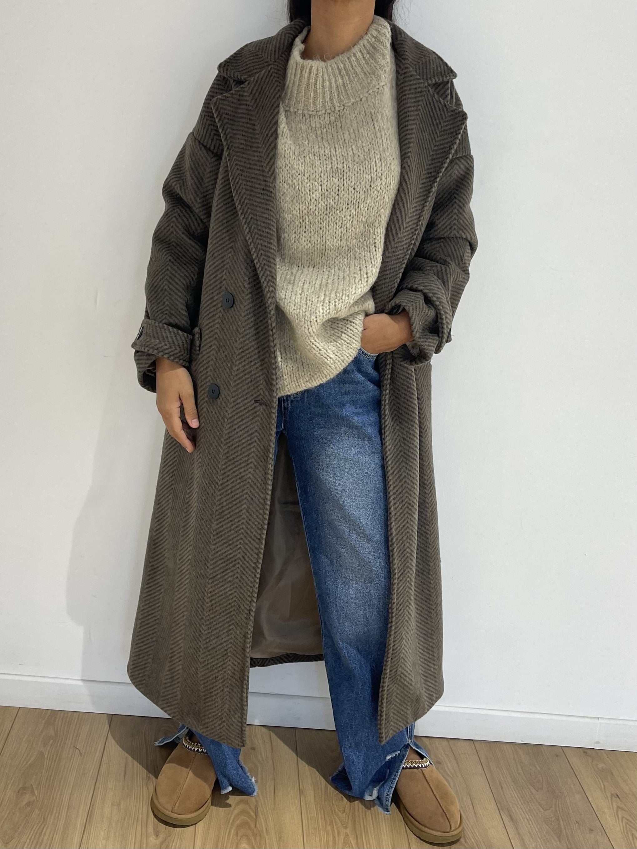 Manteau oversize à chevrons porté avec pull et jean pour un look quotidien confortable.