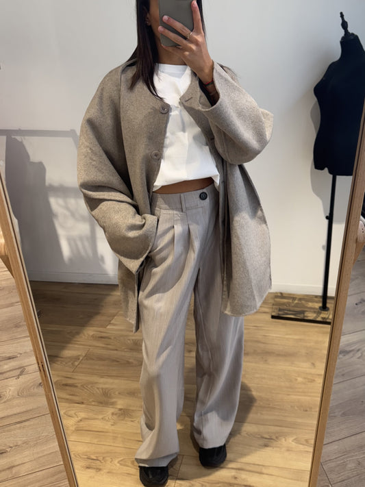 Femme portant un pantalon beige ample avec un manteau beige oversize, style minimaliste.