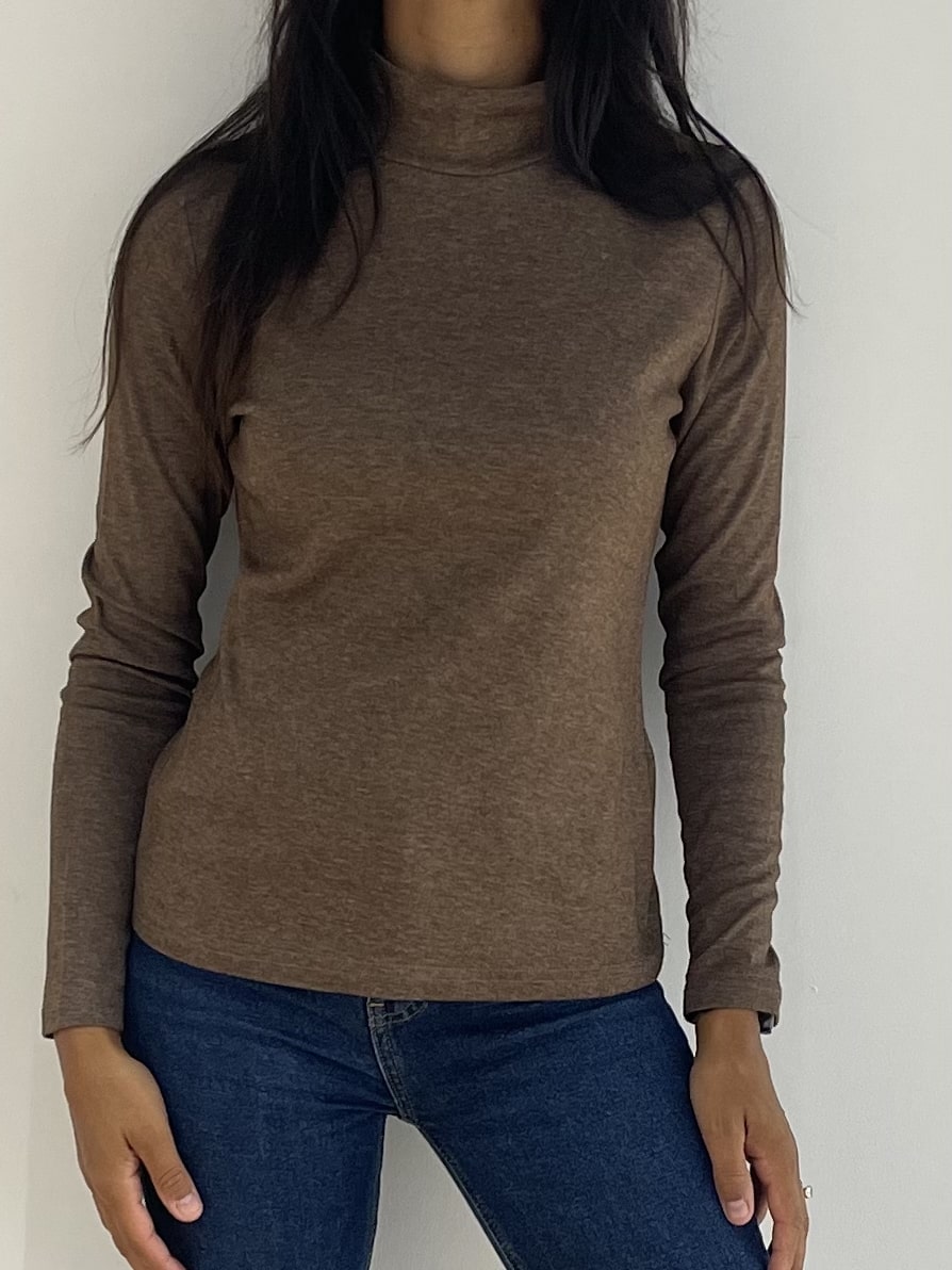 Femme présentant un pull marron en tricot fin à col montant