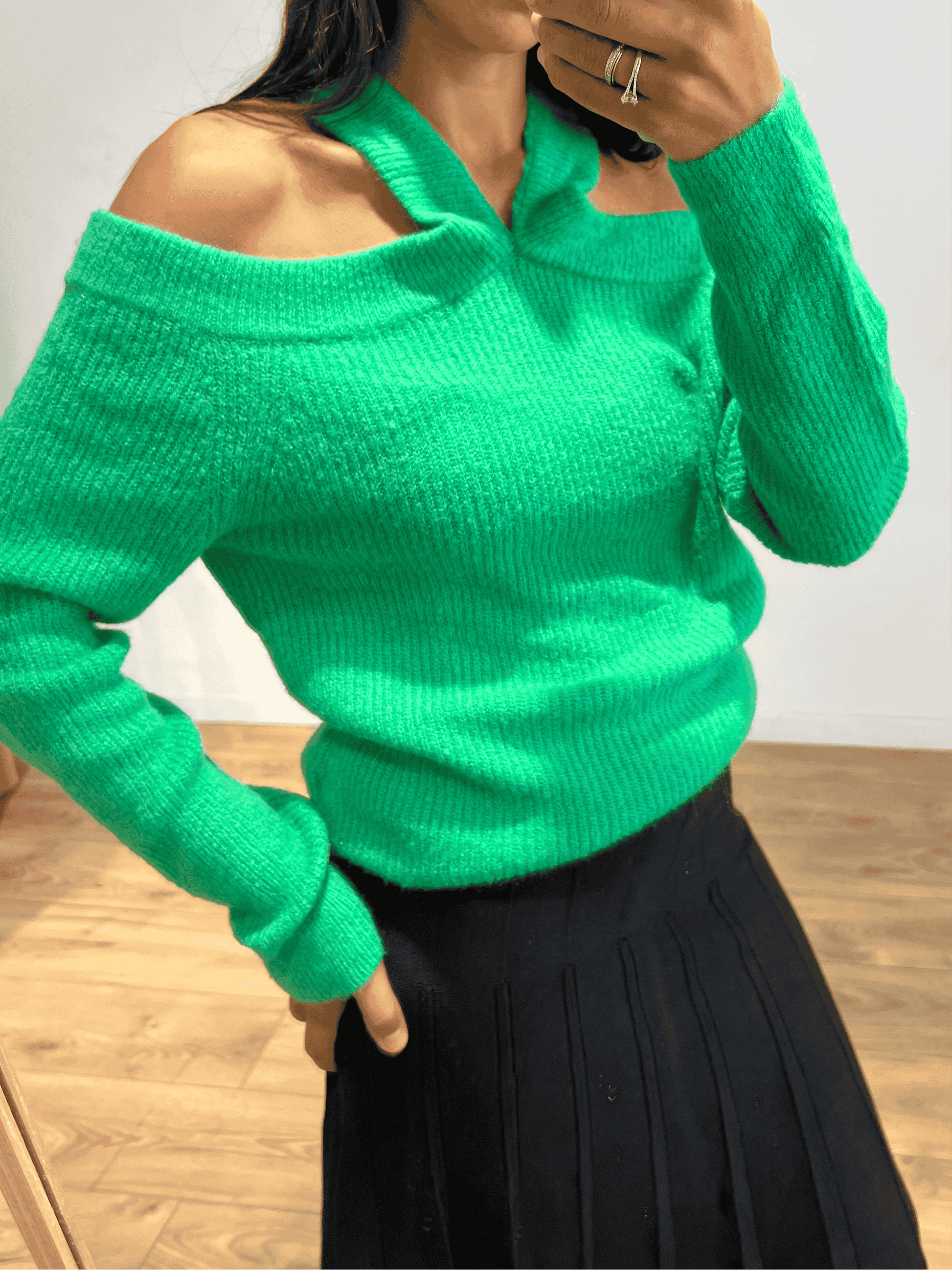 Gros plan sur le devant d'un pull vert en maille avec épaules dénudées.