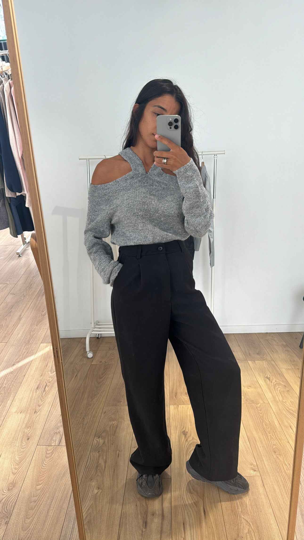 Femme portant un pull en maille gris avec épaules dénudées, vue de face.