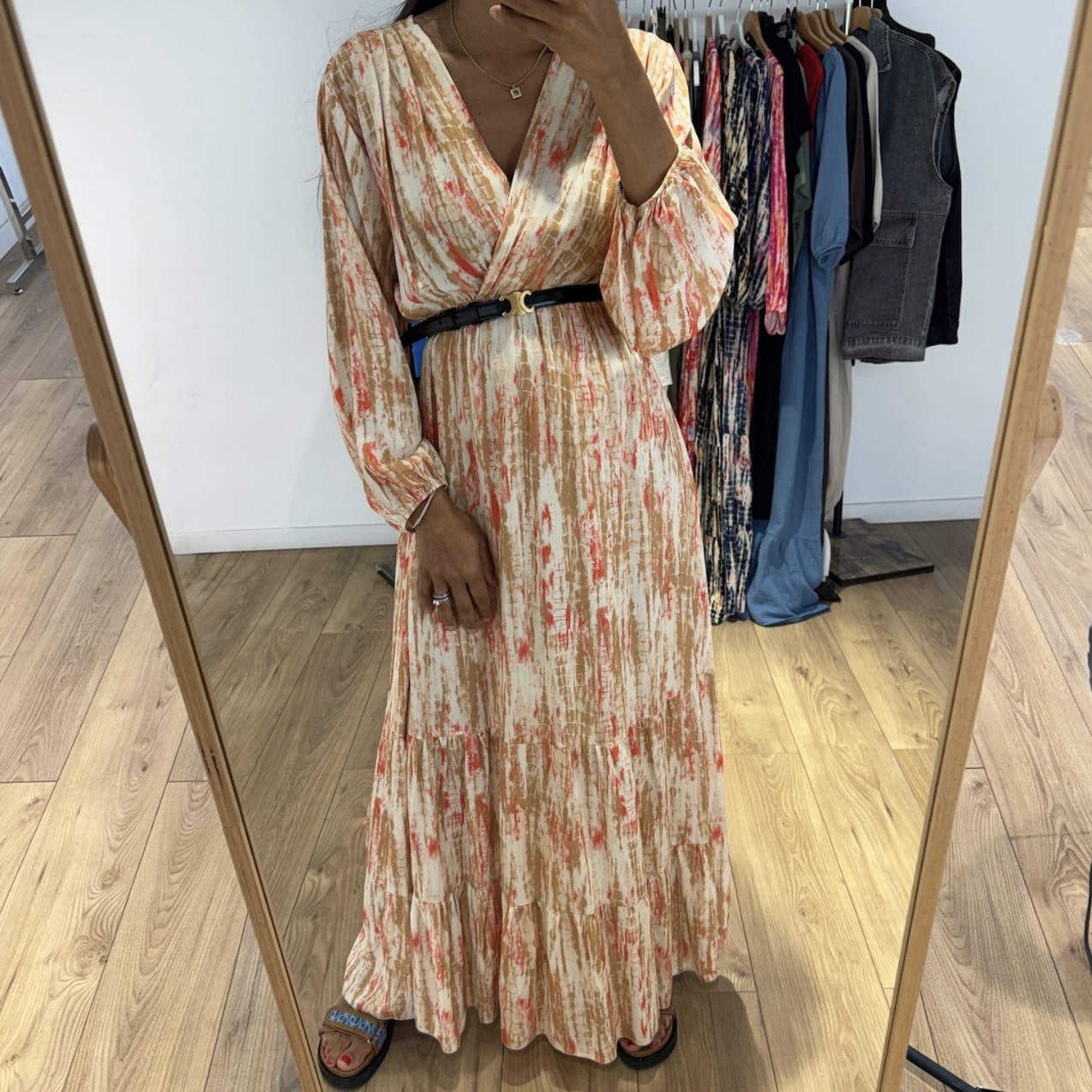 Femme portant une robe longue tie and dye en soie beige avec une ceinture noire, prise en selfie devant un miroir.