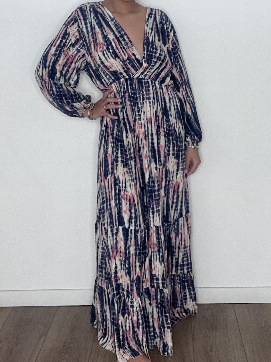 Femme portant une robe longue tie and dye en soie bleue, prise en selfie devant un mur blanc.