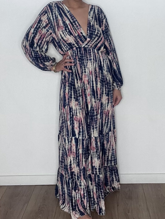 Femme portant une robe longue tie and dye en soie bleue, prise en selfie devant un mur blanc.