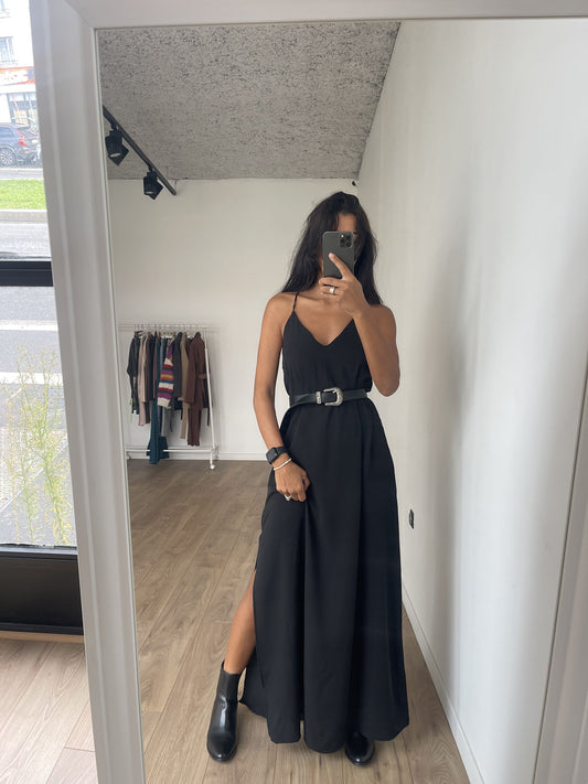 Robe noire à bretelles fines avec ceinture pour silhouette structurée.
