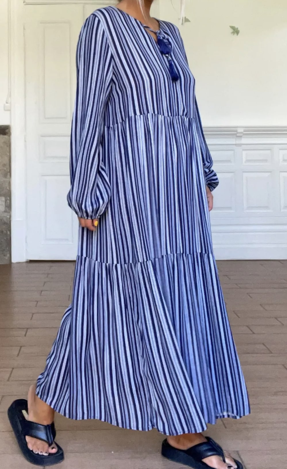 Robe longue à rayures bleues et blanches avec manches longues et encolure détaillée.