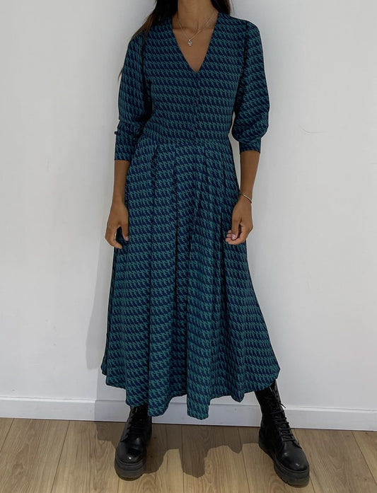 Robe midi légère à taille ajustée, col V et manches longues en tissu bleu à motifs.