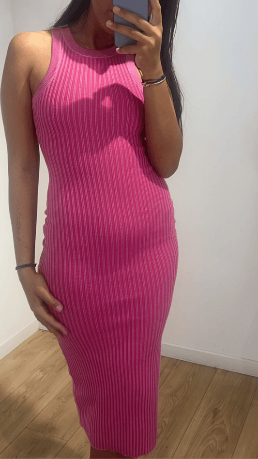 Femme portant une robe sans manches ajustée rose devant un miroir.