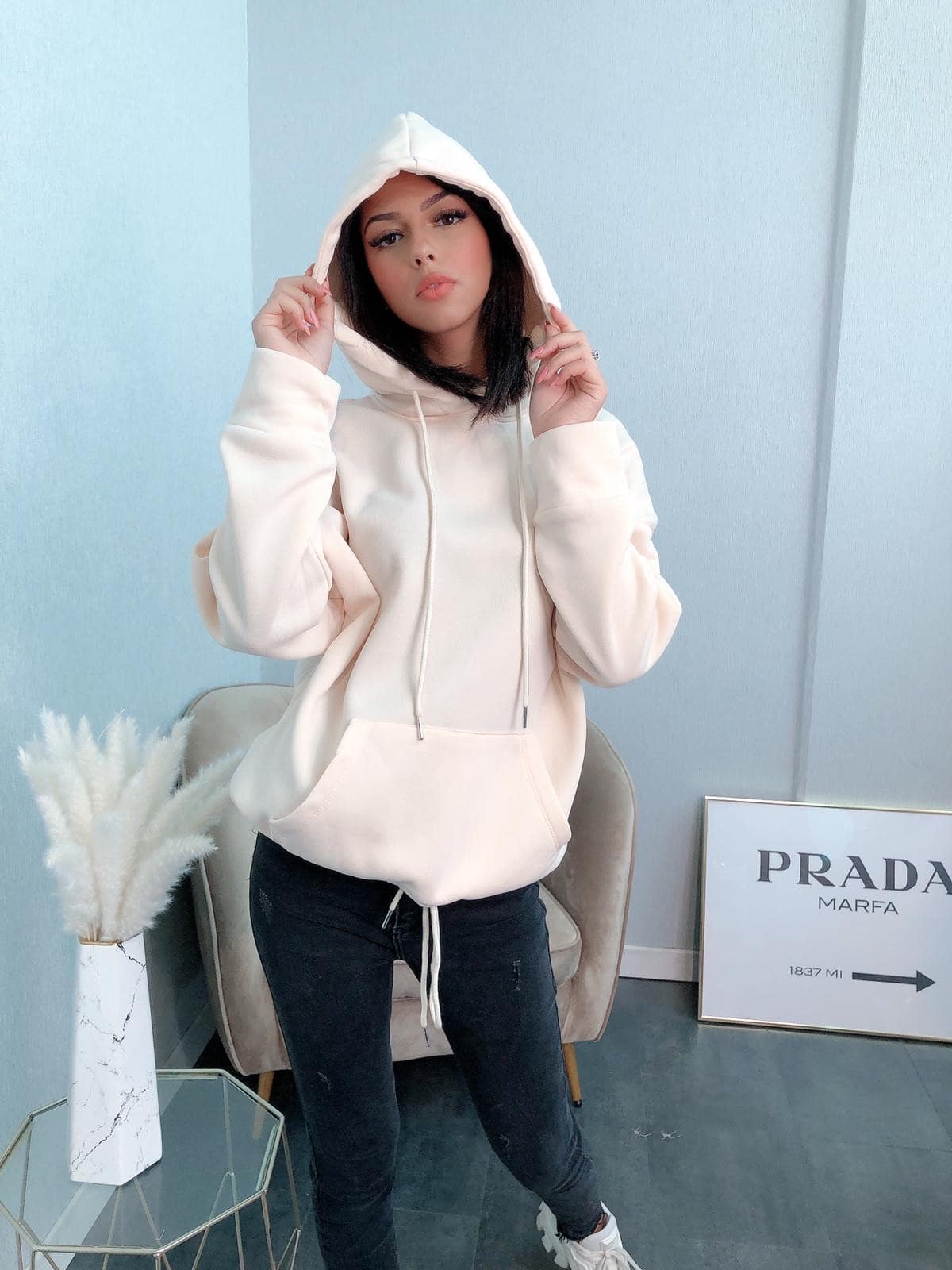 Portrait de femme en sweat à capuche beige et jeans noirs